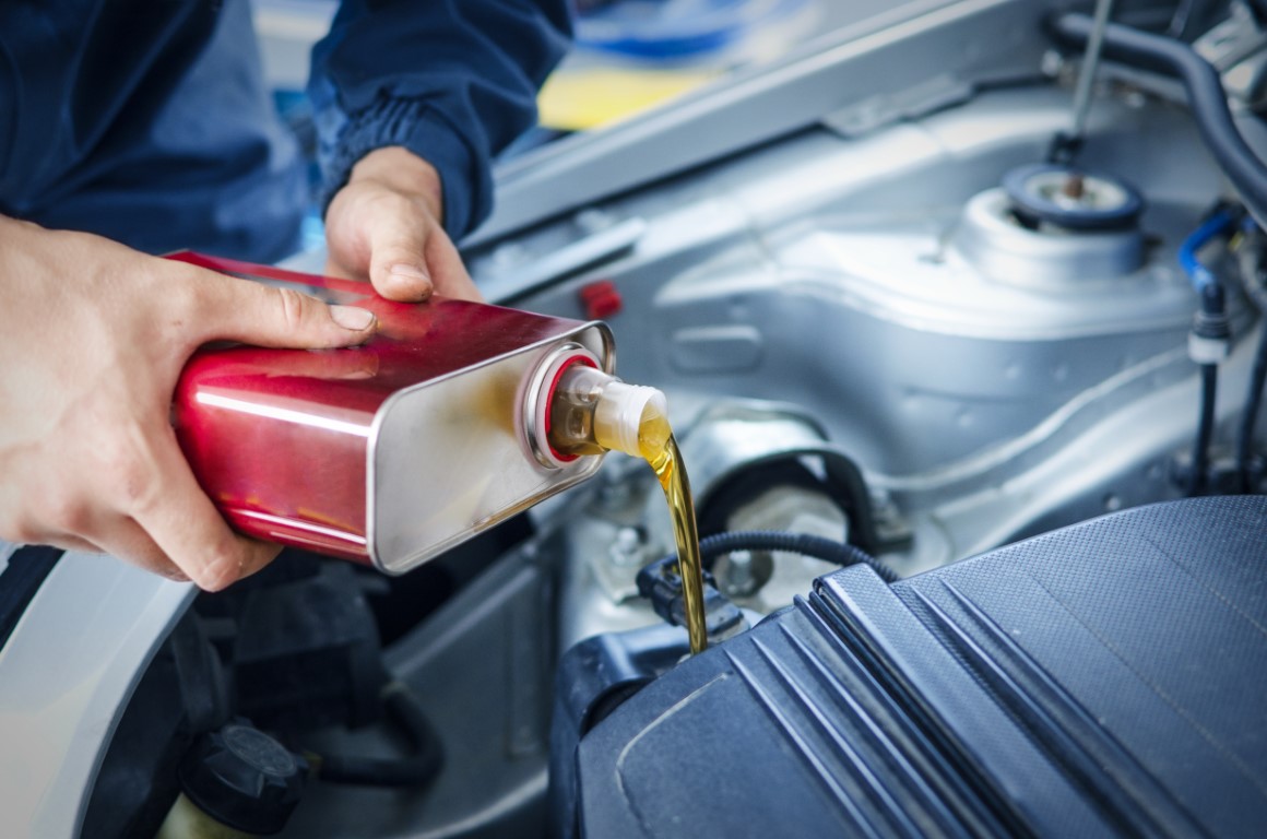 Mechanic changing engine oil on car vehicle.